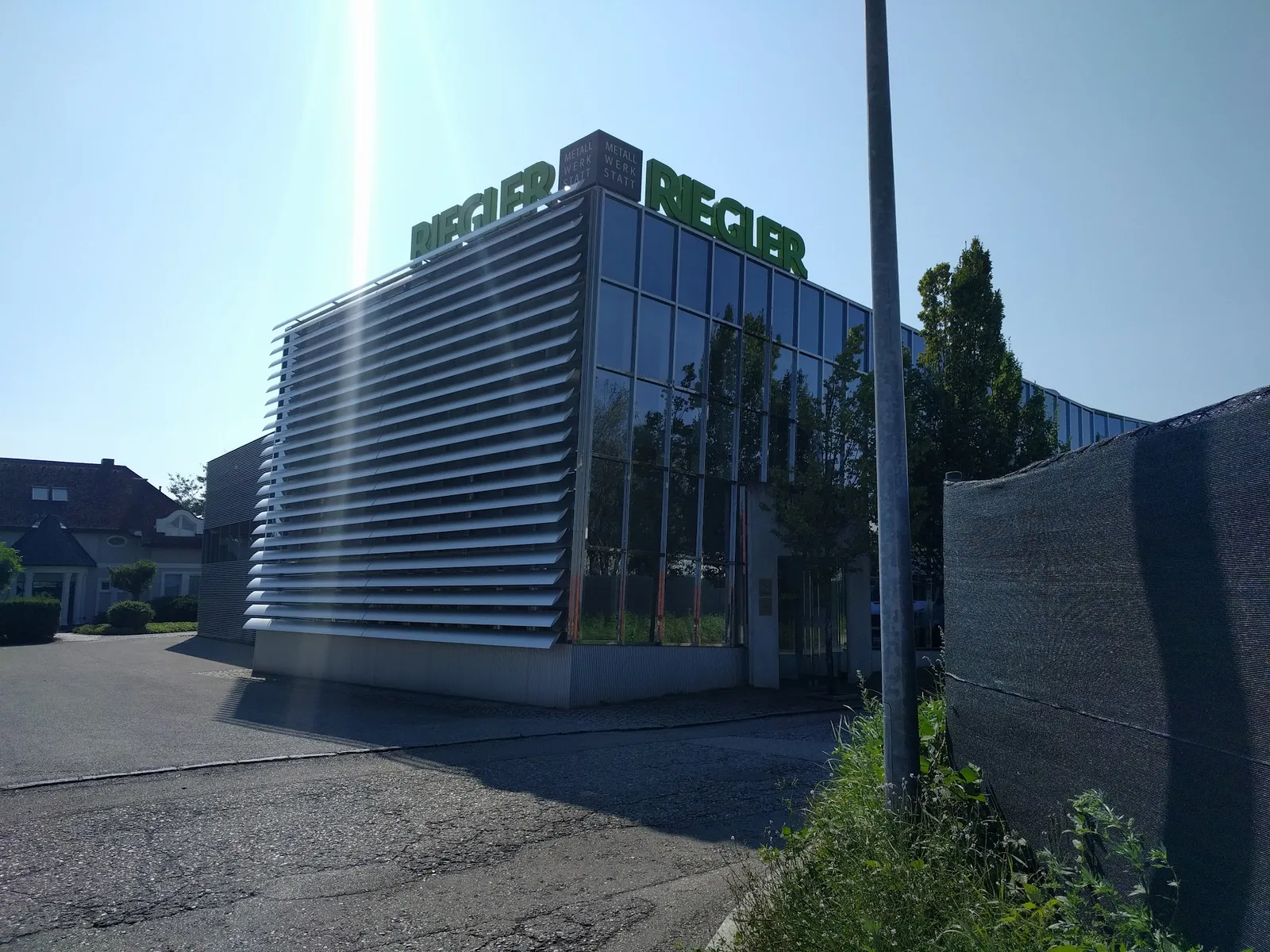 Firmengebäude mit Lamellen und grünem RIEGLER-Schriftzug im Gegenlicht