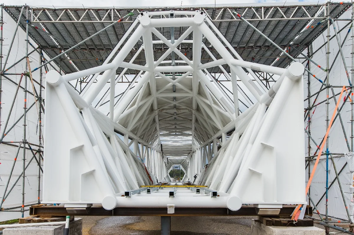 Weißes Stahlskelett einer Verbindungsbrücke im Baugerüst, Blick durch die ganze Länge